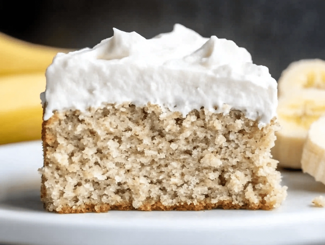 Front view of a moist healthy banana cake slice with thick whipped frosting on top