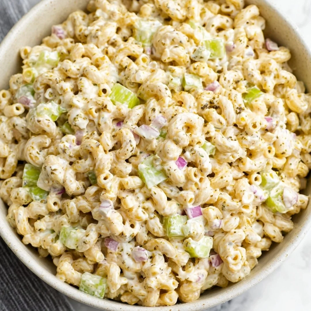 Bowl of creamy macaroni salad topped with herbs and vegetables